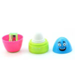 Цветен балсам за устни с усмихнат капак и острилка в розова опаковка.